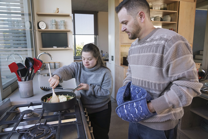 Man and woman with Down Syndrome preparing dinner in kitchen